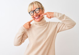 Happy middle-aged woman pointing at her smile