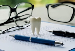 Two pens and tooth model on top of document