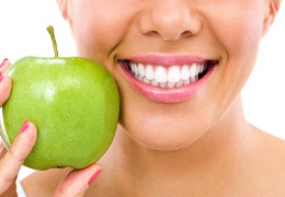 Woman enjoying apple with help of her dental implants