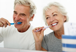Senior couple brushing their teeth in front of mirror