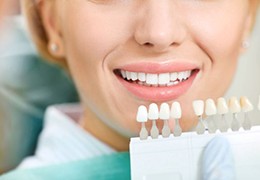 Dental shade guide next to patient’s smile