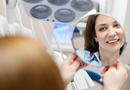 Happy dental patient’s face reflected in mirror
