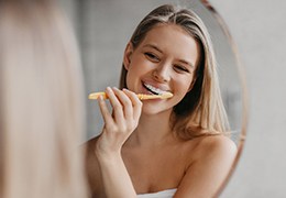 Young woman brushing her teeth in front of mirror