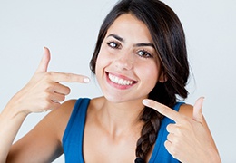 Happy woman pointing at her teeth after whitening treatment