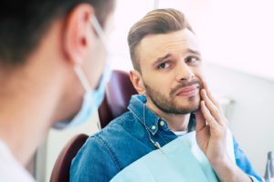 man with toothache looking to dentist for emergency care