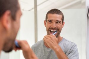 happy man following dentist&rsquo;s advice to brush his teeth