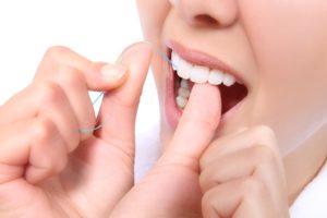 Close-up of woman’s mouth as she uses dental floss