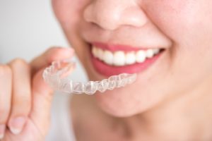 Close-up of woman’s smile as she holds SureSmile aligner