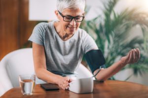 Woman with gum disease in Prestonsburg checking her blood pressure