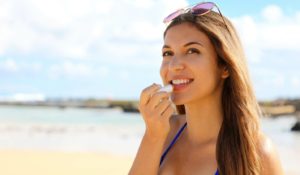 Woman applying lip balm to protect her lips from the sun