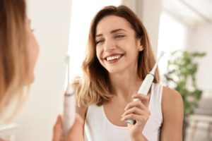 Woman in white shirt brushing her teeth to reverse gingivitis 