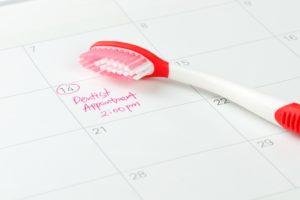 Dental checkup marked on calendar, next to red and white toothbrush