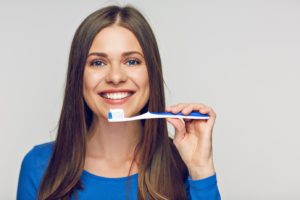 Smiling woman holding a toothbrush, trying to prevent a dental emergency