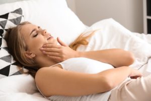 Woman in bed, suffering with a toothache