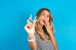 Happy woman holding clear aligner