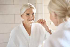 Senior woman brushing teeth in front of mirror