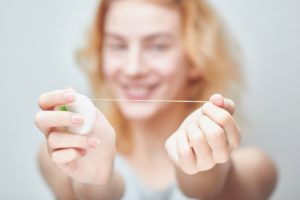 Smiling woman holding dental floss