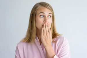 Woman covering mouth, embarrassed by bad breath