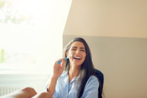 Woman sitting in desk chair, holding toothbrush