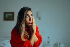 Frowning woman touching the side of her face