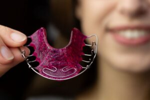 Smiling woman holding a Hawley retainer 